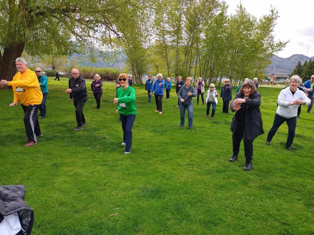Tai Chi with people in rows in the park on the grass