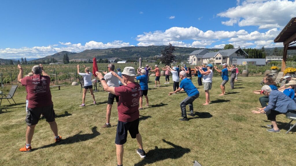 Tai Chi group with hands in the air, looking across a field