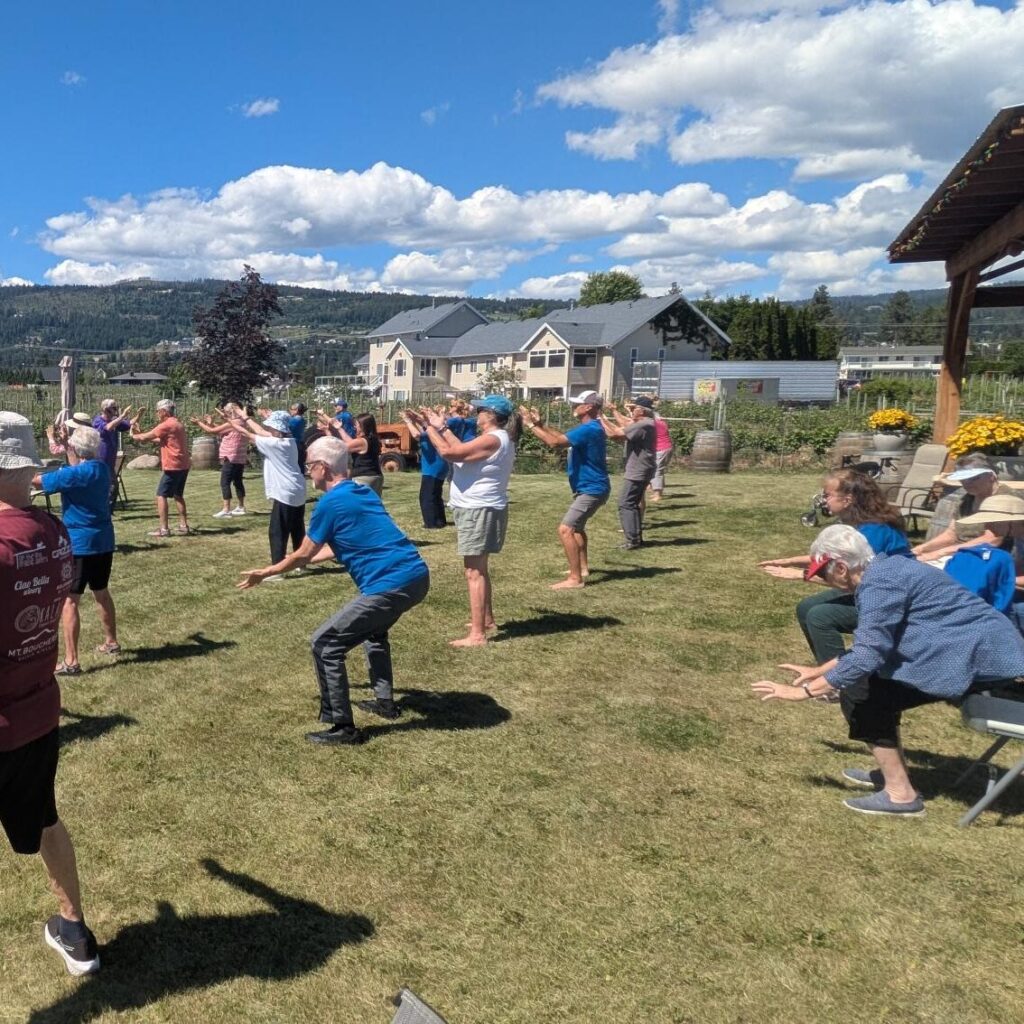 Tai Chi group with hands in the air, looking across a field